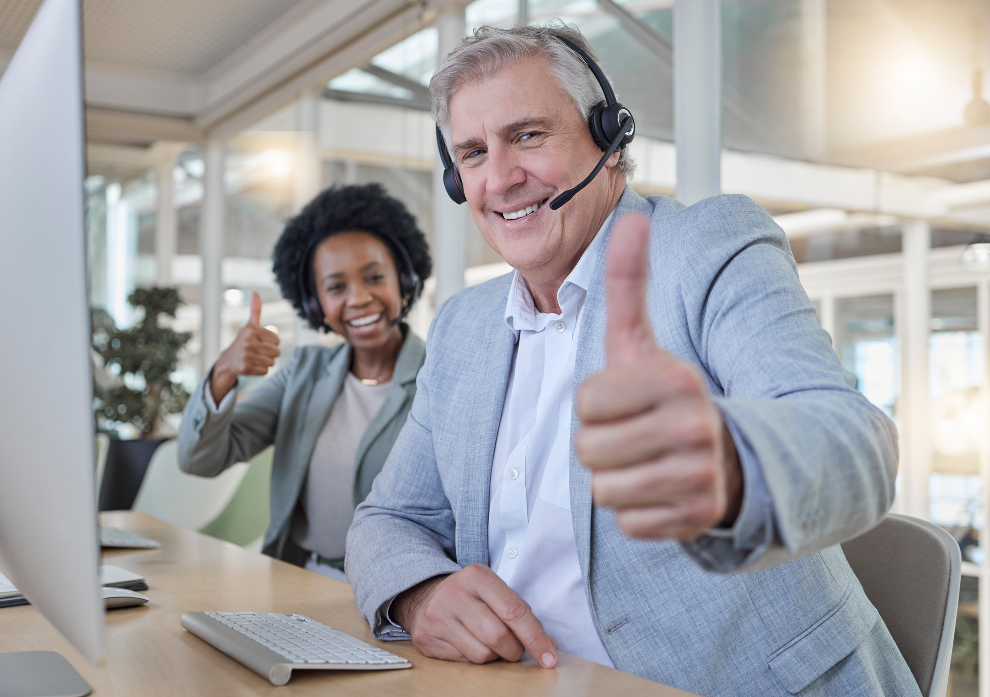 Customer Support, Thumbs up and Portrait of Call Center Employees Happy at Computer in Consulting Office. Help Desk, Smile and Mature Man with Black Woman at Advisory Agency for Crm Networking Online